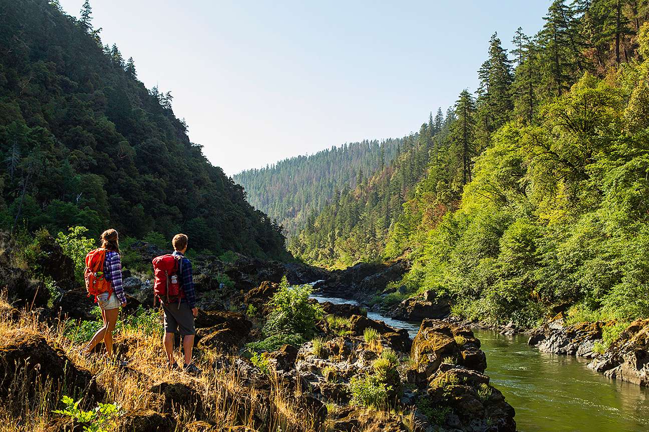 Hikers on a scenic trail, surrounded by forests, mountains, or rivers.